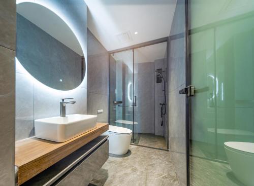 a bathroom with a sink and a toilet and a mirror at Lingxi Riverview Boutique Homestay - Phoenix Ancient Town in Fenghuang