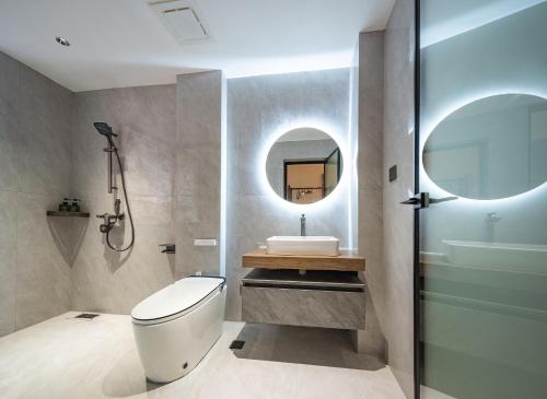 a bathroom with a toilet and a sink and a mirror at Lingxi Riverview Boutique Homestay - Phoenix Ancient Town in Fenghuang