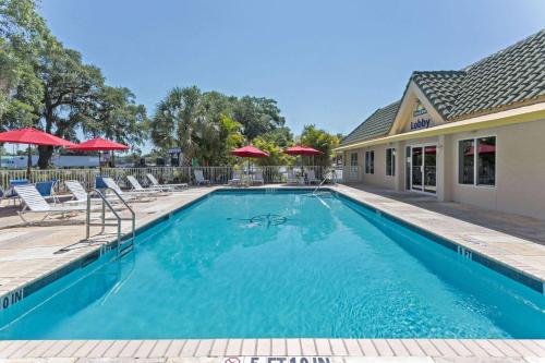 a swimming pool with chairs and umbrellas at Days Inn by Wyndham Port Charlotte Town Center in Port Charlotte