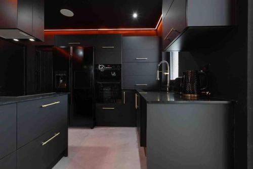 a kitchen with black cabinets and a black counter top at Luxury Couples Get-Away Glasgow in Knightswood