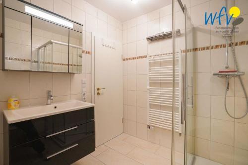 La salle de bains est pourvue d'un lavabo et d'une douche avec une porte en verre. dans l'établissement Villa Schoen 58091, à Borkum