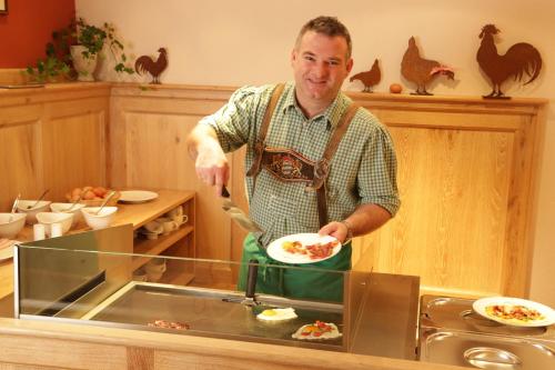 a man in a kitchen holding a plate of food at Pension Schweizerhaus Garni in Weyarn
