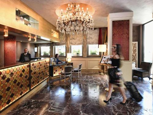 een vrouw die langs een bar loopt in een hotellobby bij Hotel Papadopoli Venezia - MGallery Collection in Venetië