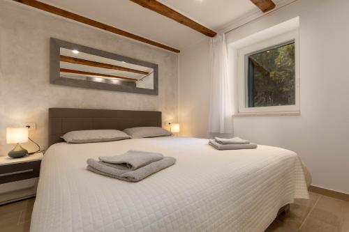 una camera da letto con un letto bianco e asciugamani di Stancia Rosa - cozy apartment a Poreč (Parenzo)