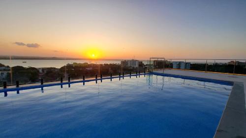 a large swimming pool with the sunset in the background at Urban by CityBlue Hotel, Dar es Salaam in Dar es Salaam