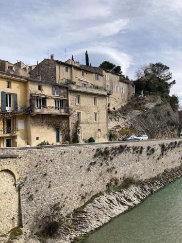 un groupe de bâtiments sur une colline au bord de l'eau dans l'établissement Belle vue sur le Pont Romain, à Vaison-la-Romaine