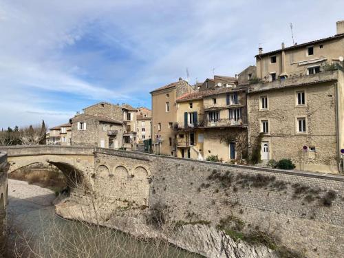 un pont sur une rivière dans une ville avec des bâtiments dans l'établissement Belle vue sur le Pont Romain, à Vaison-la-Romaine