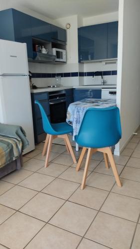une cuisine avec une table et deux chaises bleues dans l'établissement Vaux Pontaillac Le soleil et la mer, à Vaux-sur-Mer