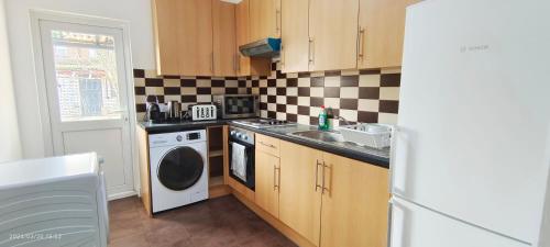a kitchen with a washer and a sink and a dishwasher at Maple House near Wembley Stadium in London