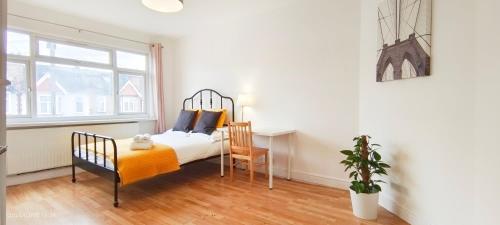 a bedroom with a bed and a desk and a window at Maple House near Wembley Stadium in London