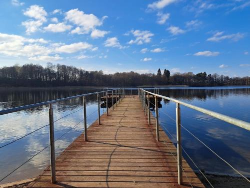 a wooden bridge over a lake on a sunny day at BORNE militaria wygodne mieszkanei dla 5 osób in Borne Sulinowo