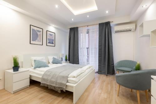 a white bedroom with a bed and a chair at Downtown Nature Apartment in Budapest