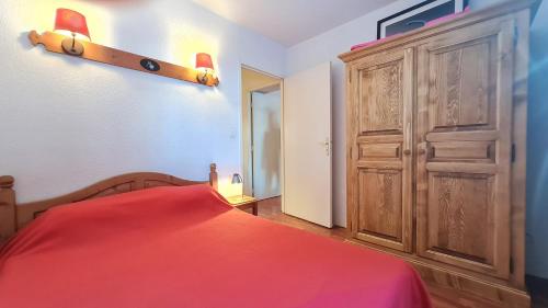 - une chambre avec un lit rouge et une armoire en bois dans l'établissement Edelweiss - 2 - Appart RDC - 4 pers, à Les Deux Alpes
