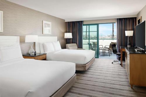 a hotel room with two beds and a television at DoubleTree by Hilton San Pedro in San Pedro