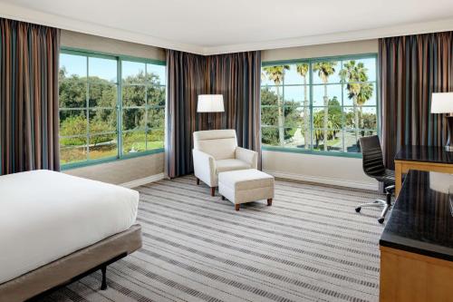 a hotel room with a bed and a chair and windows at DoubleTree by Hilton San Pedro in San Pedro