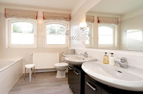 a white bathroom with two sinks and a toilet at Ferienwohnung Nordwind in Westerland