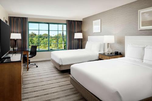 a hotel room with two beds and a desk and a television at DoubleTree by Hilton San Pedro in San Pedro