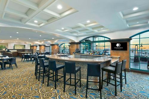a restaurant with a bar with chairs and tables at DoubleTree by Hilton San Pedro in San Pedro