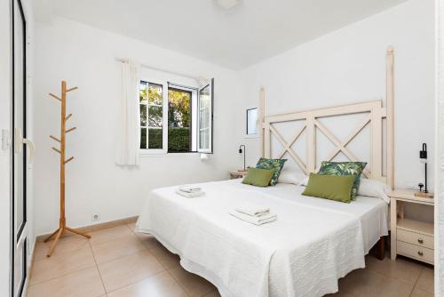 a white bedroom with a large bed with green pillows at Apartamentos en Son Bou in Son Bou