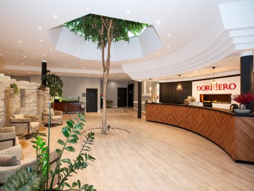 a hotel lobby with a palm tree in the center at DORMERO Hotel Worms in Worms