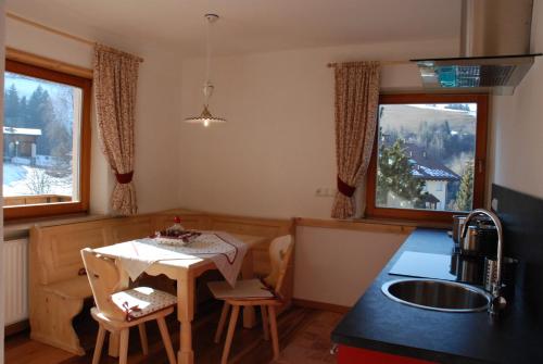 - une cuisine avec une table et un évier ainsi que 2 fenêtres dans l'établissement Villa Moroder, à Ortisei