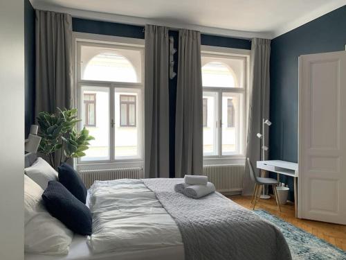 a bedroom with a large bed with two windows at Großzügiger Wiener Altbau gleich neben Schönbrunn in Vienna