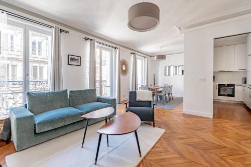 un salon avec un canapé bleu et une table dans l'établissement Champs Elysées Stylish Flat 2BR 6PPL, à Paris