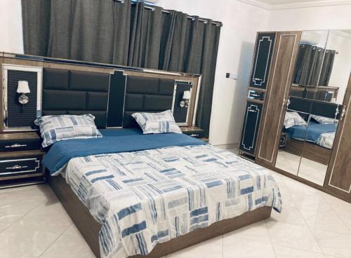 een slaapkamer met een bed en een grote spiegel bij The Peacock Mansion in Kumasi