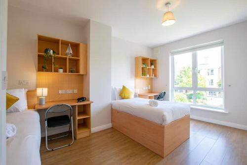 a bedroom with a bed and a desk and a window at 74 - 4 Bed Townhouse With Parking by Shortstays in Galway