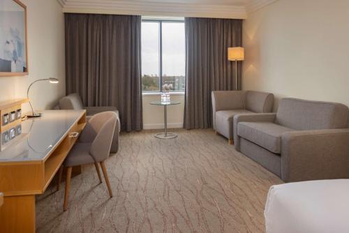 a hotel room with a bed and a couch and a table at Hilton Dublin Airport in Cloghran