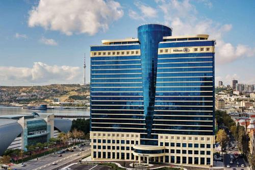 a tall building with blue windows in a city at Hilton Baku in Baku