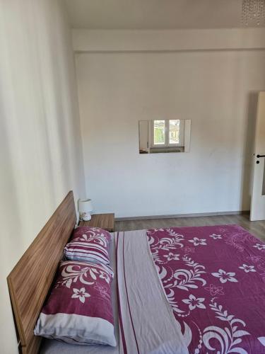 1 dormitorio con 1 cama con manta morada y ventana en Appartamento vicino università, en Piacenza