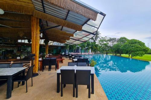 The Par Phuket SHA Plus في كاتو: مطعم بطاولات وكراسي بجانب مسبح