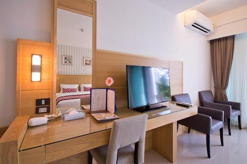 a room with a desk with a television and chairs at The Par Phuket SHA Plus in Kathu