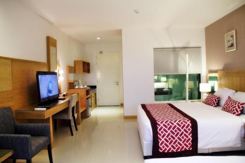 a hotel room with a bed and a desk and a television at The Par Phuket SHA Plus in Kathu