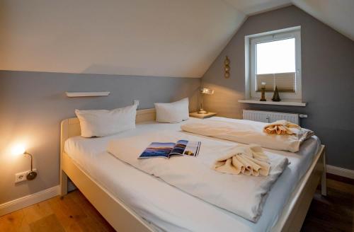 ein großes weißes Bett in einem Zimmer mit Fenster in der Unterkunft Kleine Buhne in Wenningstedt-Braderup