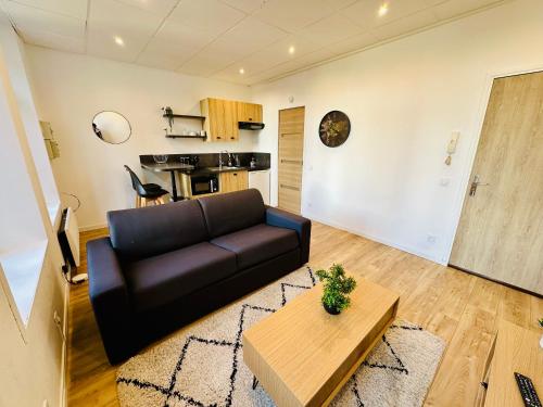 un salon avec un canapé noir et une table dans l'établissement Vue dégagée #1, à Boulogne-sur-Mer