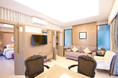 a living room with a couch and a tv at The Par Phuket SHA Plus in Kathu
