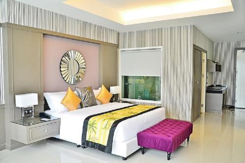 a bedroom with a large bed with a purple stool at The Par Phuket SHA Plus in Kathu