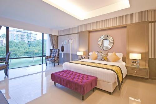 a bedroom with a large bed and a purple bench at The Par Phuket SHA Plus in Kathu