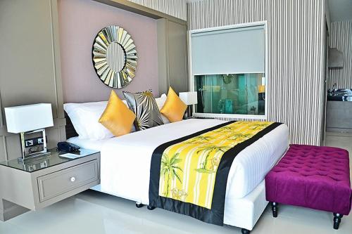 a bedroom with a large bed and a purple stool at The Par Phuket SHA Plus in Kathu