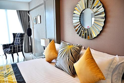 a bedroom with a bed with pillows and a mirror at The Par Phuket SHA Plus in Kathu
