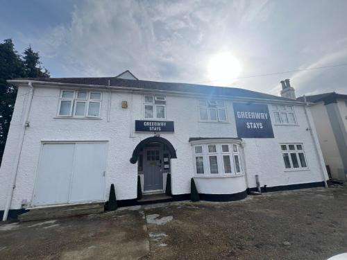 un edificio de ladrillo blanco con una señal azul en OYO Greenway Stays, en Uxbridge