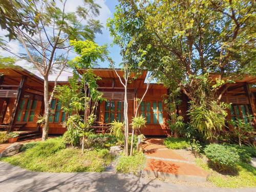 une maison en bois avec des arbres devant elle dans l'établissement Areeya phubeach resort wooden house, à Ban Chong Phli