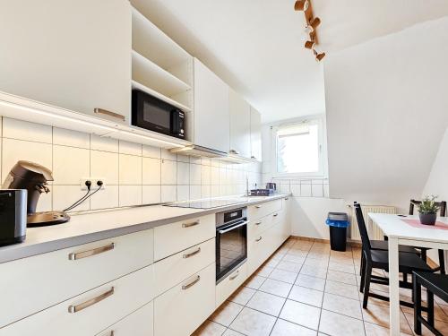 a kitchen with white cabinets and a table with chairs at Centerline Apartments Solingen in Solingen