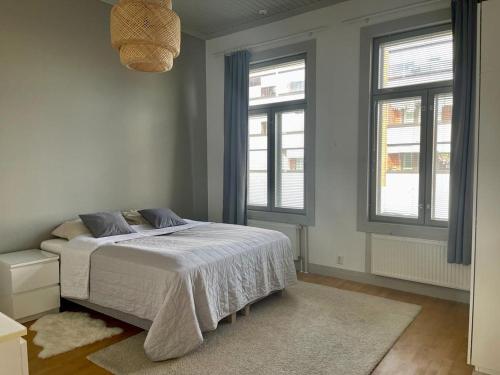 a white bedroom with a bed and two windows at 19th century house with parking hall, own entrance and terrace in Vaasa