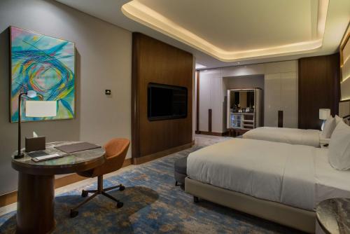 a hotel room with a bed and a desk and a tv at Hilton Tashkent City in Tashkent