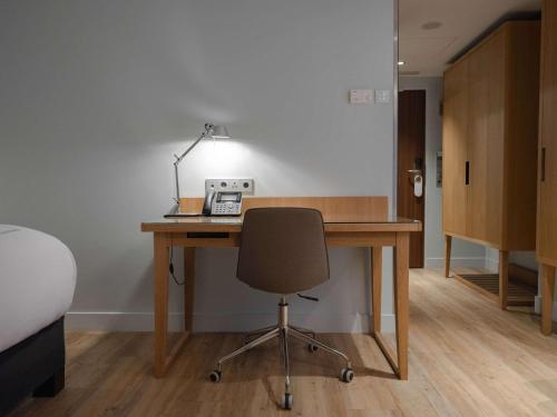 an office with a desk with a chair and a lamp at Swissôtel Amsterdam in Amsterdam