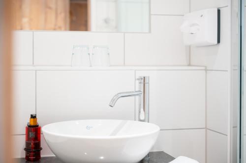 a white sink in a bathroom with white tiles at Snooze Apartments in Holzkirchen