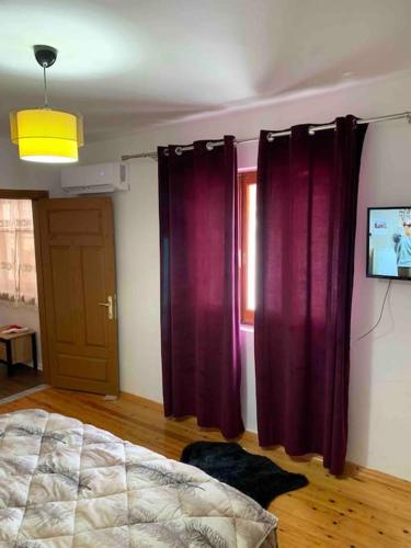 a bedroom with purple curtains and a bed and a television at Traditional Bazaar Home2 in Korçë
